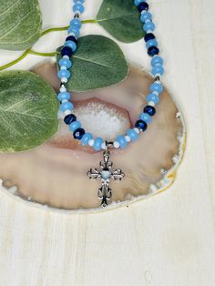 "The adorable blue heart cross beaded necklace is hand made in the USA. Made with a beaded chain and a lobster claw clasp. This necklace is the perfect accessory for any women's wardrobe.   This necklace is a great womens gift.  The necklace is a length of 17\" - 19\"" Beaded Cross Pendant Necklace As A Gift, Adjustable Blue Cross-shaped Jewelry, Adjustable Blue Cross Necklace, Blue Adjustable Cross Necklace, Beaded Cross Pendant Jewelry Gift, Beaded Cross Pendant Jewelry For Gift, Light Blue Heart Beads Jewelry For Gift, Light Blue Heart Beads Jewelry Gift, Adjustable Cross Beaded Necklaces For Gifts