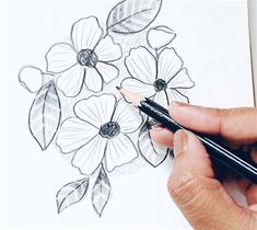 a person drawing flowers on paper with a marker