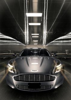 a black car in a parking garage with lights shining on the cars headlamps