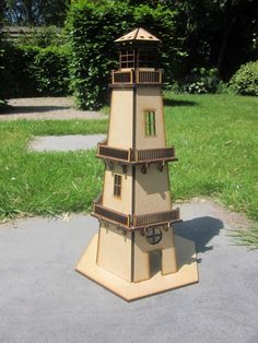 a cardboard model of a tower in the middle of a park with grass and trees behind it