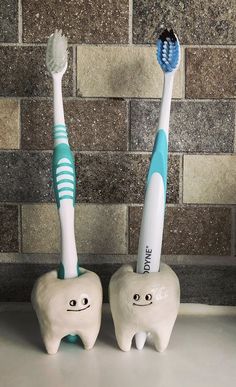 two toothbrushes sitting next to each other in front of a brick wall,