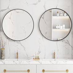 two round mirrors on the wall above a white vanity with gold handles and brass accents