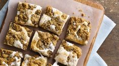 there are many squares of food on the cutting board with icing and crumbs