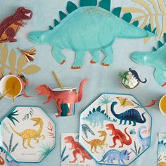 dinosaur plates, cups and spoons on a table