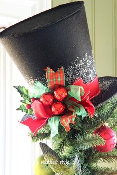 a top hat decorated with red and green bows on a christmas tree in front of a window