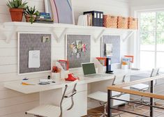 a desk with two laptops on top of it next to a chair and bookshelf