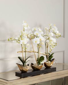 three vases with white flowers are sitting on a table