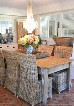 a dining room table with wicker chairs and a chandelier hanging from the ceiling