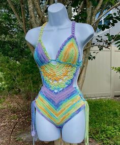 a crocheted swimsuit is displayed on a mannequin in front of a tree