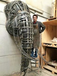 a man standing next to a giant metal horse head