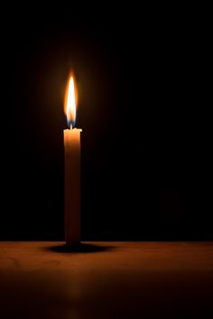 a lit candle in the dark with one light on it's side and two candles at the end