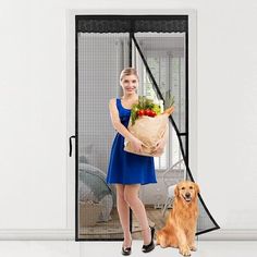 a woman standing in front of an open door holding a bag of vegetables and a golden retriever