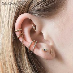 a woman wearing three different types of ear piercings