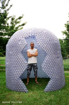 a man standing in front of a large metal object on the grass with his arms crossed