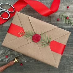 an envelope wrapped in brown paper with a wax stamp on it and red ribbon around it