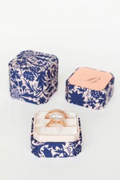 an engagement ring sits in a blue and white box next to it's matching wedding band