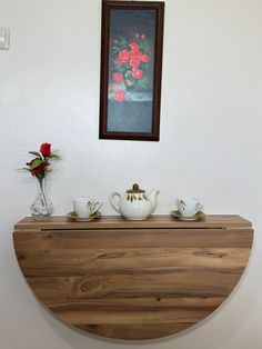 a wooden table topped with cups and saucers next to a vase filled with flowers