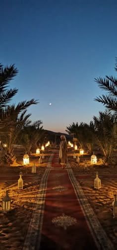 a long red carpet with candles on it in the middle of a desert area at night