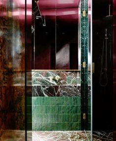 a bathroom with green and red tiles on the walls, shower stall and sink area