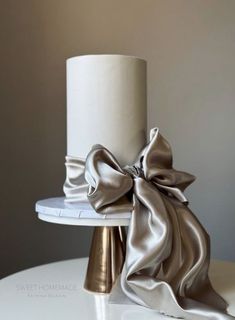 a white cake with a silver bow on it's top sitting on a table