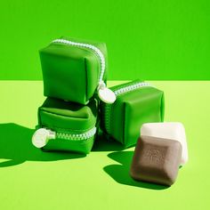 three green and white bags sitting next to each other on top of a green surface