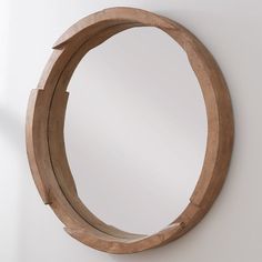 a circular mirror mounted to the side of a white wall next to a wooden frame