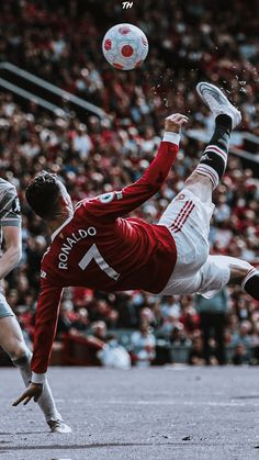 a man kicking a soccer ball on top of a field in front of a crowd