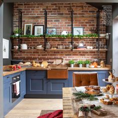 a brick wall in a kitchen with blue cabinets and wooden shelves filled with food items