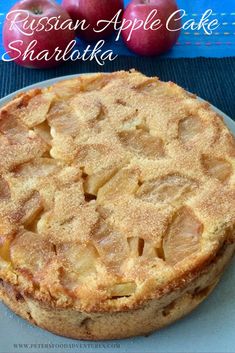 an apple cake is on a plate with apples in the background and text overlay that reads russian apple cake sharlka