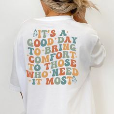 a woman wearing a white t - shirt that says it's a good day to bring comfort to those who need it most