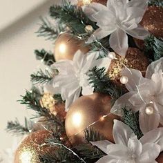 a christmas tree decorated with gold and white balls, poinsettis and lights