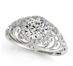 a diamond ring with filigrees on the sides and an intricate design in the middle