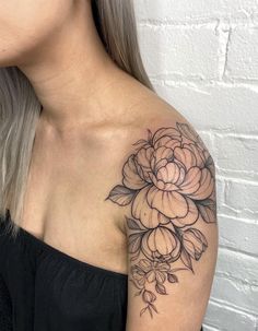 a woman's shoulder with a flower tattoo on her left arm and the upper half of her body