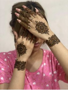 a woman holding her hands up to her face with hendi tattoos on their arms