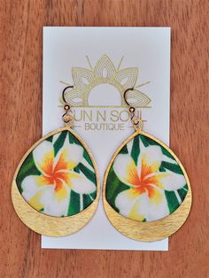 a pair of earrings with yellow and white flowers on the inside, sitting on top of a card