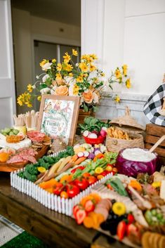 a table filled with lots of different types of vegetables and fruits next to a sign