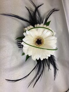 a white and black flower with feathers on it's centerpiece, sitting on a bed sheet