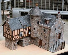 a model of a castle made out of bricks on a wooden table in front of a building