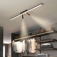 an open closet with clothes hanging on shelves and lights above the closet door, along with other items