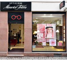 a store front with pink and black signage on the window displays an advertisement for opticians