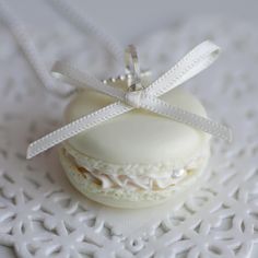 a white macaroon is sitting on a doily with a ribbon around it