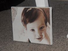 a white teddy bear sitting on the floor next to a photo frame with a baby's face