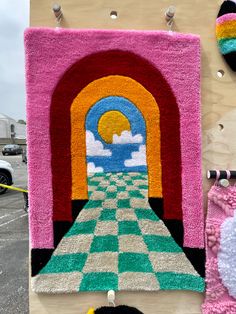 an art piece is displayed on the side of a building with colorful rugs hanging from it's sides