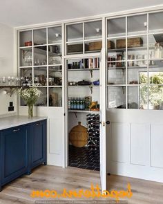 an open pantry with wine bottles and glasses on the shelves next to a counter top