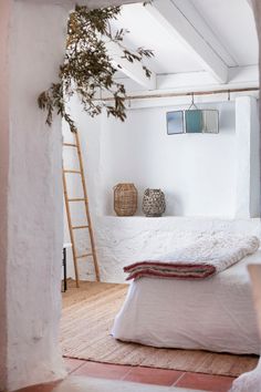 a bed sitting under a window next to a wooden ladder on top of a floor