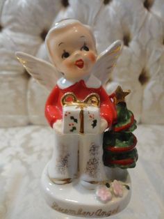 an angel figurine holding a christmas present