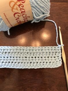 a crocheted piece of yarn next to a knitting needle on a wooden table