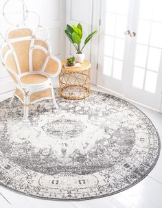 a round rug with a chair and potted plant next to it in a white room