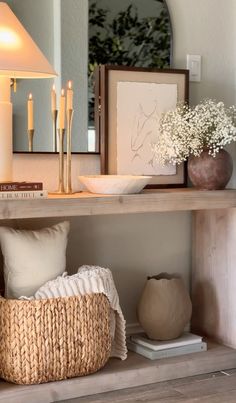 a shelf with candles, vases and other items on it in front of a mirror