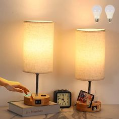 two lamps that are next to each other on a table with an alarm clock in front of them